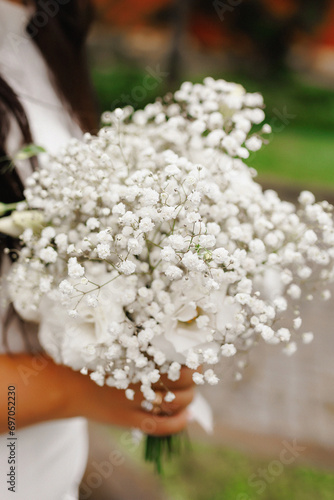 a young girl in a white wedding dress holds a bouquet