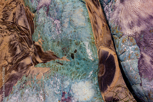 Contrasting brown and turquoise rocks on the beach in an interesting abstract pattern.