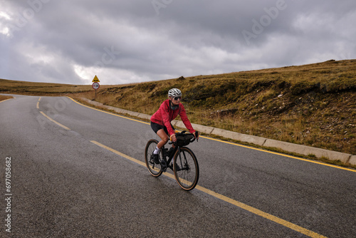 Female cyclist in bike packing tour.Bikepacking travel.Female cyclist is riding through foggy mountain landscape.Adventure cycling concept. Woman cycling in the nature.Transalpina road.Parâng Mountain