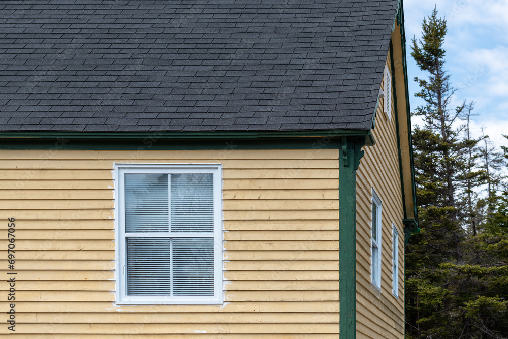 Yellow and white colored wooden shed. The small wood structure is a vibrant yellow color and is covered in wooden cape cod siding with small glass windows. The peaked roof is covered in black shingles Yellow and white colored wooden shed. The small wood structure is a vibrant yellow color and is covered in wooden cape cod siding with small glass windows. The peaked roof is covered in black shingles