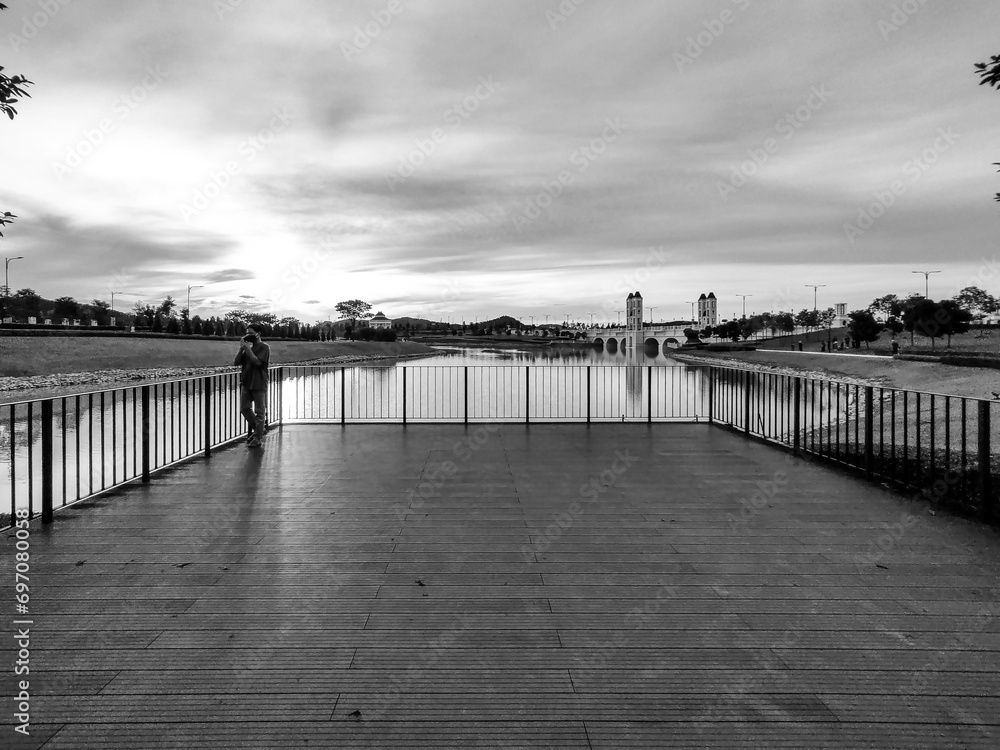 Puncak Alam, Selangor, Malaysia, November 10, 2022: Embracing Eco Grandeur: A Magnificent View of the Bridge, a Harmony of Nature, lake, Architecture and a one man on the frame in black and white.