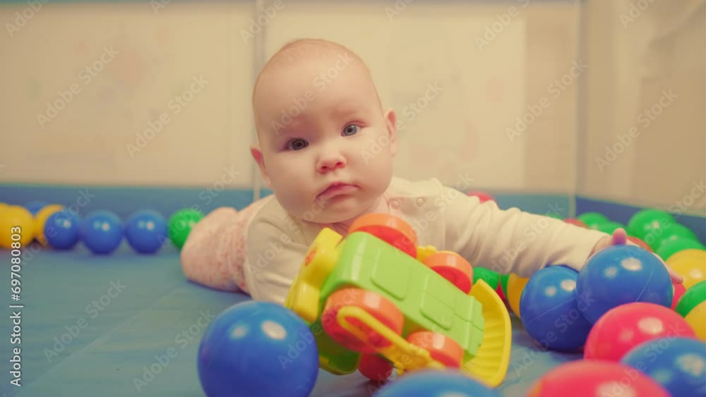 Cute little baby girl playing with colorful toys in a nursery. Cute little baby girl playing with colorful toys in a nursery.