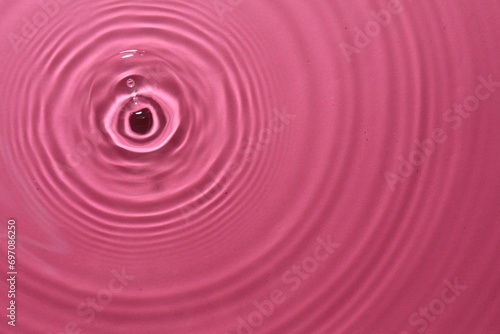 Rippled surface of clear water on bright pink background, top view