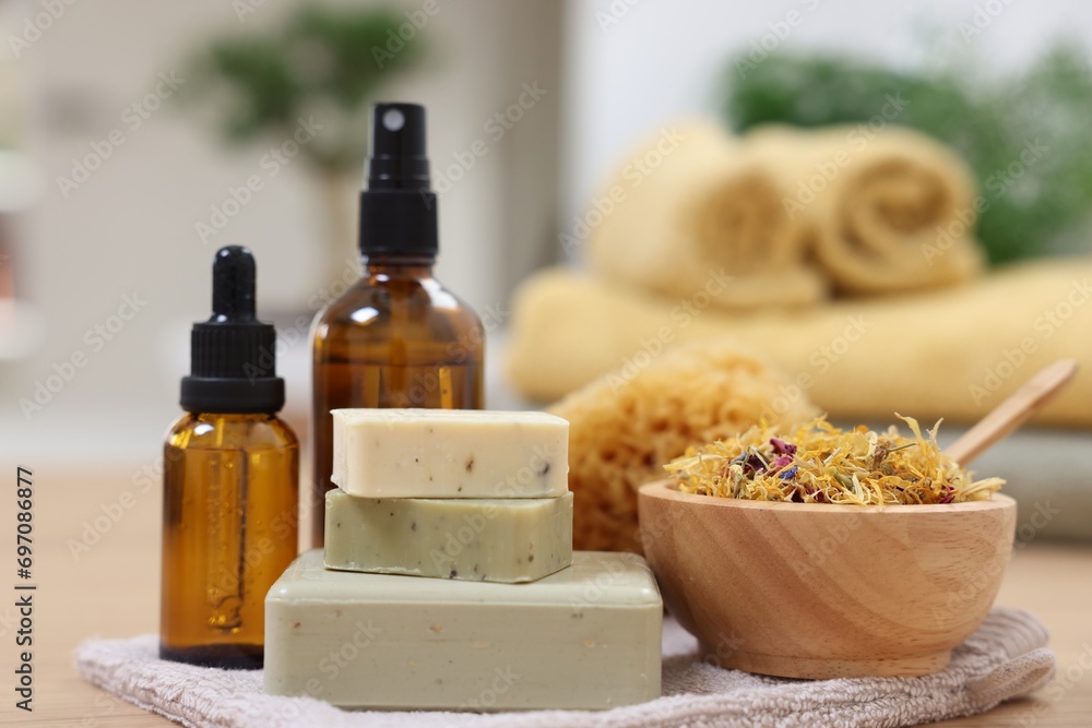 Bottles of essential oils, bowl with dry flowers, soap bars and natural sponge on light wooden table, closeup. Spa therapy Bottles of essential oils, bowl with dry flowers, soap bars and natural sponge on light wooden table, closeup. Spa therapy