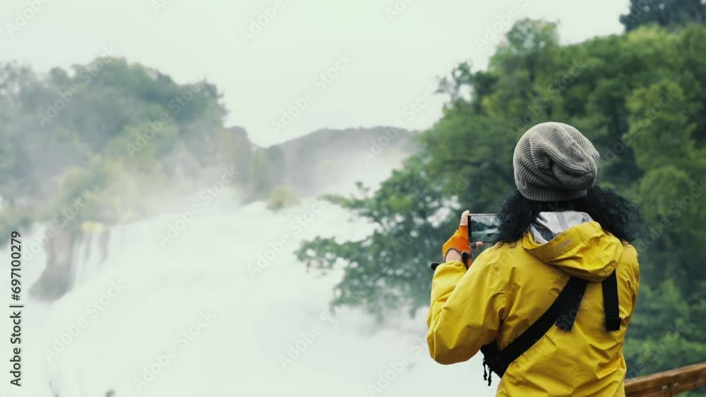 Young lady traveler, looking stylish, takes a photo of a mountain lake using her smartphone. Attractive young woman of Caucasian ethnicity Young lady traveler, looking stylish, takes a photo of a mountain lake using her smartphone. Attractive young woman of Caucasian ethnicity