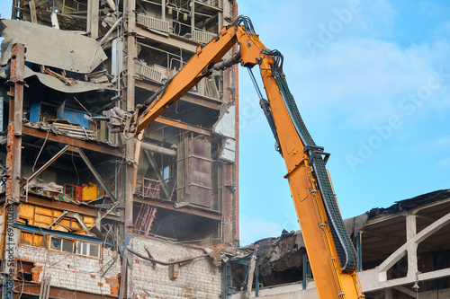 Destroying of old industrial building by excavator destroyer
