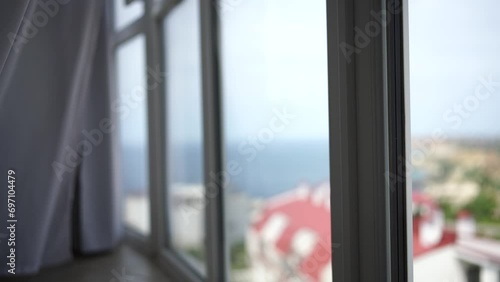 Sea view through the window with white transparent curtains slowly swaying in the wind. Resort, apartment with sea view. Leisure, relax, beauty, travel. photo