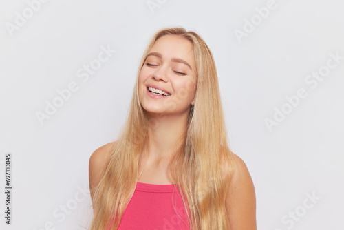 Portrait of pretty girl with long golden hair in pink top over background with closed eyes, beautiful people concept, copy space