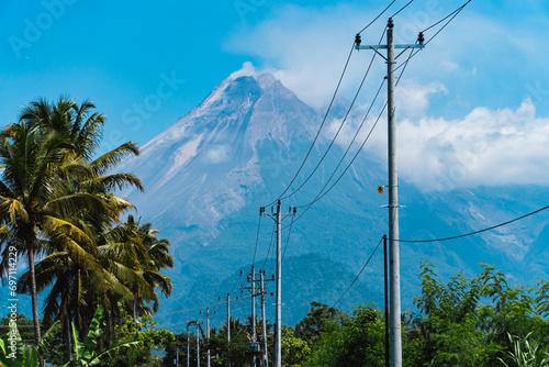 The beauty of Mount Merapi can be seen very clearly from a distance with the highway and electricity poles in front of it. The majesty of Mount Merapi on a hot day with a blue sky as a background