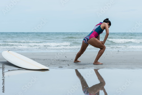 Photography Asian woman standing on the beach, she is warming up by stretching her leg