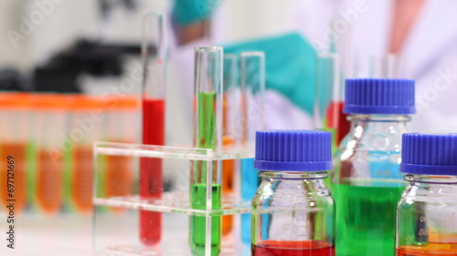 laboratory setting with colorful liquids in test tubes and a person wearing a lab coat and gloves.