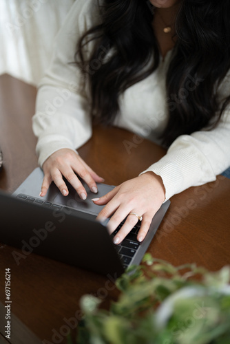 Woman working, sitting at her desk while typing on laptop