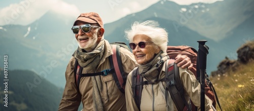 Elderly Caucasian couple hiking in mountains with gear, enjoying adventure.