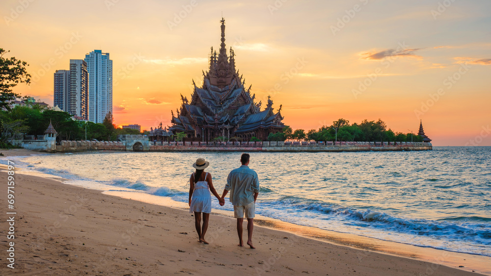 A diverse multiethnic couple of European men and Asian women visit The Sanctuary of Truth wooden temple in Pattaya Thailand at sunset A diverse multiethnic couple of European men and Asian women visit The Sanctuary of Truth wooden temple in Pattaya Thailand at sunset