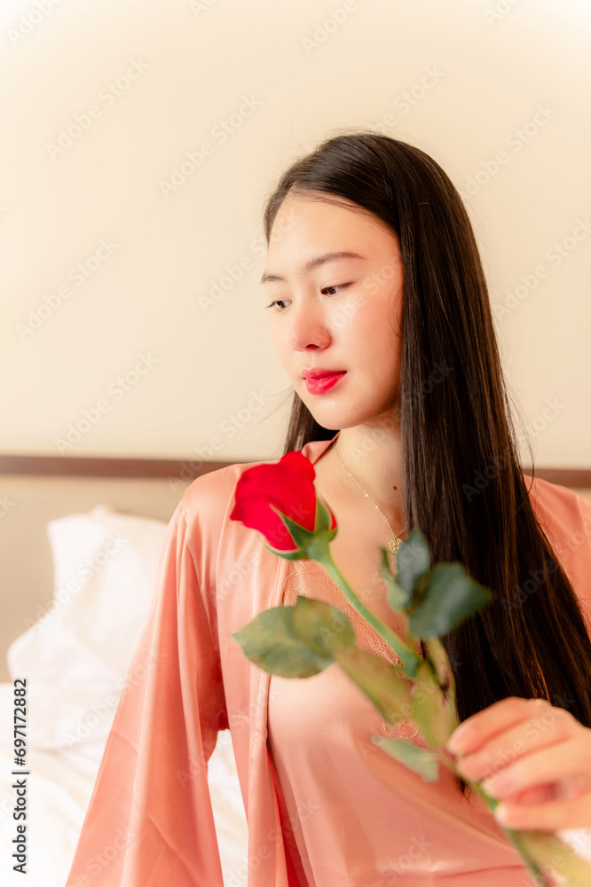 woman in pajamas colored rose gold With a red rose on the bed resting in the morning, Background concept, closeup flower. woman in pajamas colored rose gold With a red rose on the bed resting in the morning, Background concept, closeup flower.