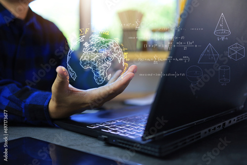 Math and physics equation concept with student hand holding globe with quotations function of geometric and law of motion in front of laptop screen on desktop photo