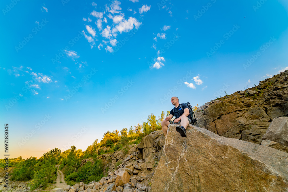Man Enjoying Serene View from Majestic Rock. A man sitting on top of a large rock