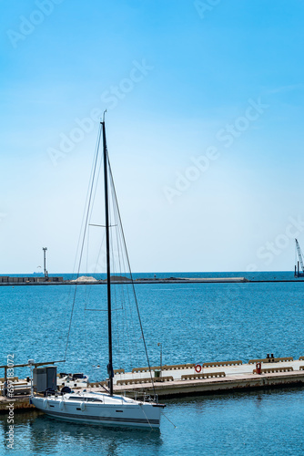 A Serene Sailboat Gracefully Floating by the Dock. A sailboat in the water near a dock