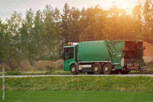 A recycling truck collects garbage bins on a suburban road. The vehicle provides a valuable service for the environment and city. Ecological and save the earth concept. Trash and garbage separation.