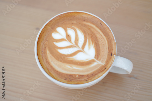 Top view of hot latte coffee with latte art in the white cup on the wooden table. Copy space.