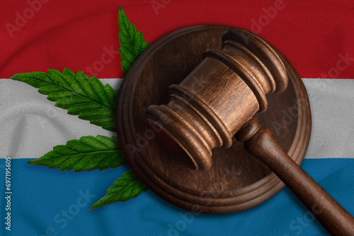 Justice wooden gavel with cannabis leaf on the Flag of Luxembourg. Illegal growth of cannabis plant and drugs spreading