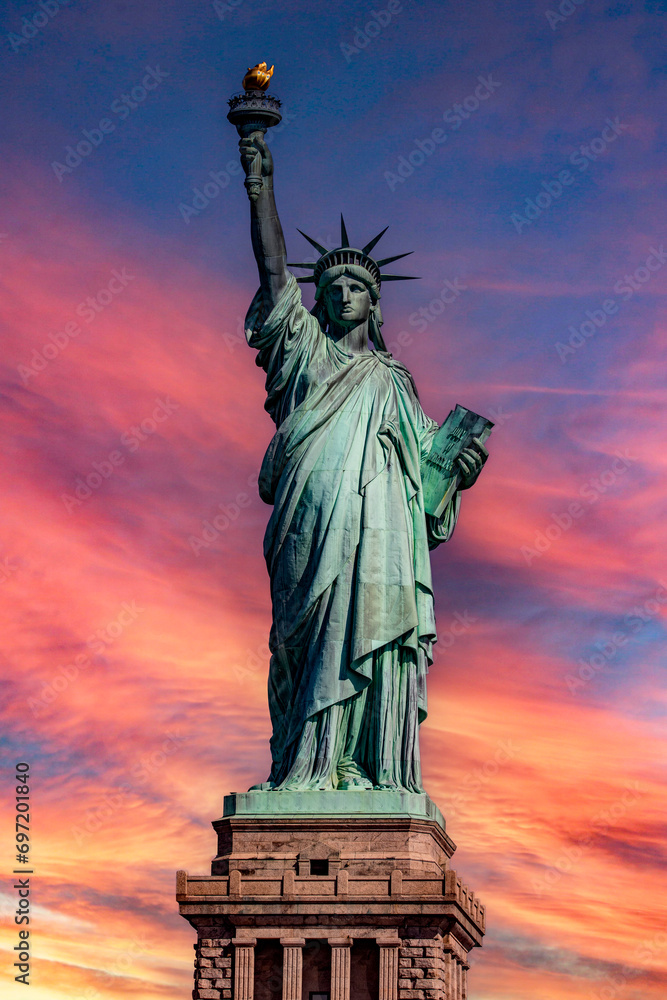 Fototapeta premium Vertical photograph of the Statue of Liberty in the Big Apple, under a reddish sky at sunrise, monument known as the lady of New York around the world
