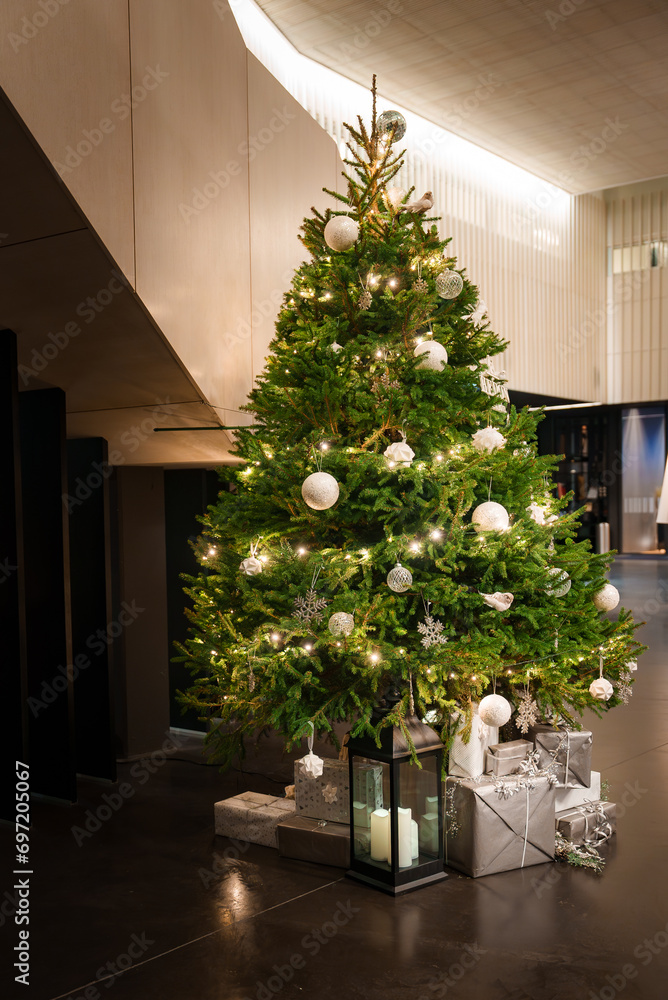Decorated Christmas tree in a lobby with many presents under the tree. Christmas mood and spirit. 