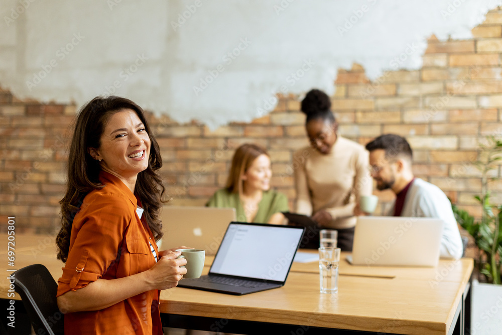Business woman working on laptop with her young multiethnic startup team working in the modern office Business woman working on laptop with her young multiethnic startup team working in the modern office