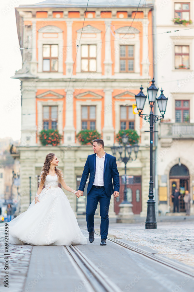Obraz premium the bride and groom look at each other and hold hands on the cit