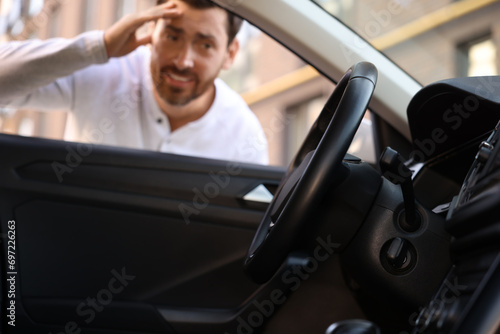 Automobile lockout, key forgotten inside, selective focus. Emotional man looking through car window photo