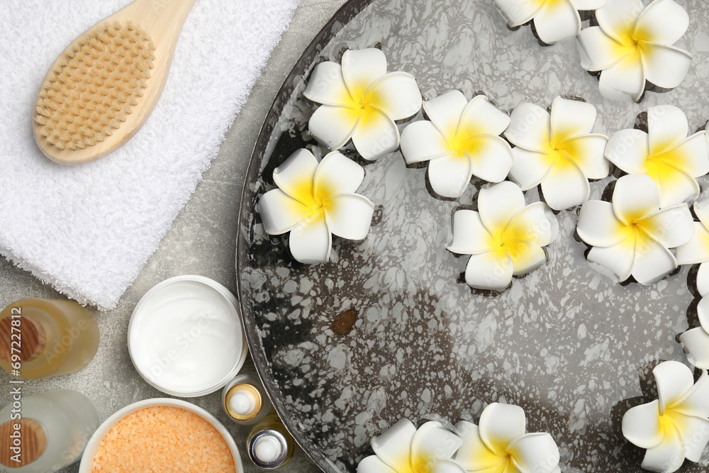 Bowl of water with flowers and different spa supplies on light grey table, flat lay Bowl of water with flowers and different spa supplies on light grey table, flat lay