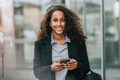 Portrait of smiling female business professional holding smart phone photo