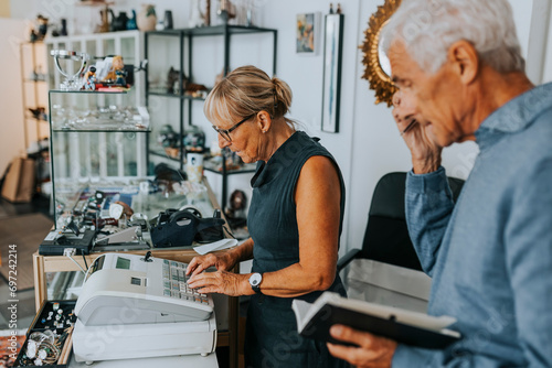 Male and female entrepreneurs standing at checkout while working in antique shop photo