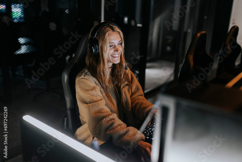Smiling woman playing video game in illuminated gaming center photo