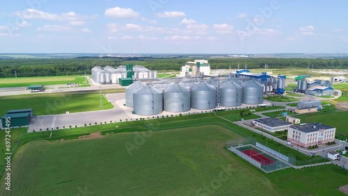 Large silver granary. Storage of grain. Factory for the production of mixed fodders. Factory for processing agricultural products. Feed Mill. Modern agricultural manufacture on field. Grain elevators  photo