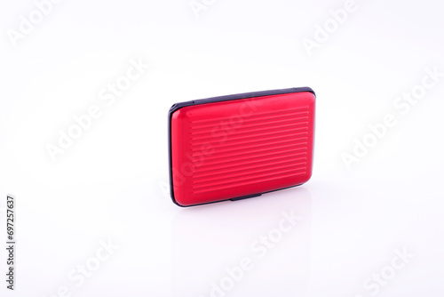 Red plastic credit card case on white reflective background. 