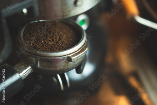 Close up ground arabica coffee from an electric grinder inside portafilter ready for brewing good espresso in cafe