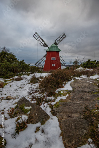 Typical historical red wooden windmill in a winter landscape. The building is located on a rock on the coast. Evening in Stenungsund, Sweden photo