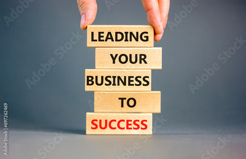 Leading your business to success symbol. Concept words Leading your business to success on wooden blocks. Beautiful grey table grey background. Leading your business to success concept. Copy space.