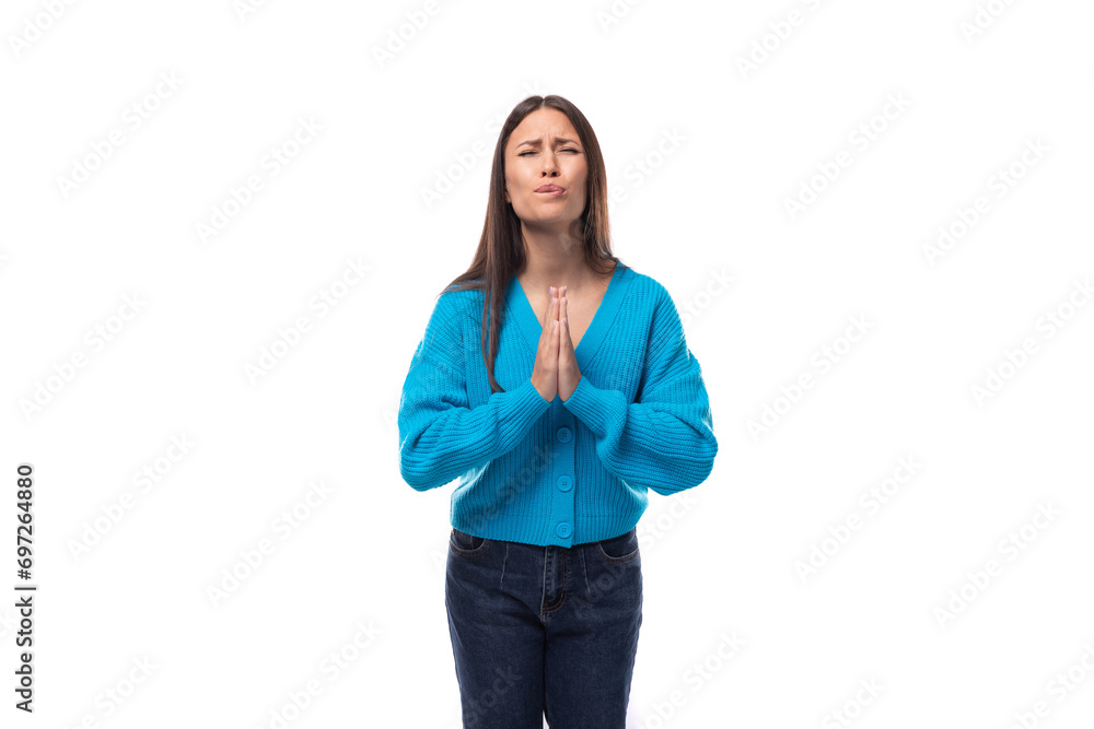 charming caucasian woman with black long straight hair is dressed in a blue sweater on a white background. people lightstyle concept charming caucasian woman with black long straight hair is dressed in a blue sweater on a white background. people lightstyle concept