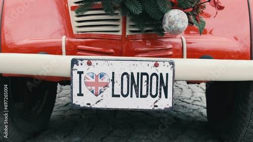A red vintage car decorated with New Year's decorations, with a license plate I love London. Close-up. photo