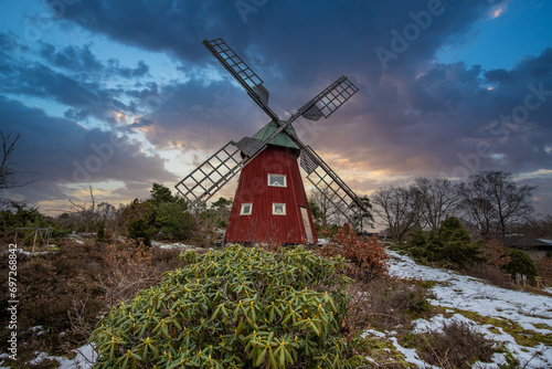 Typical historical red wooden windmill in a winter landscape. Sunset on the coast on a rock. Stenungsund in Sweden