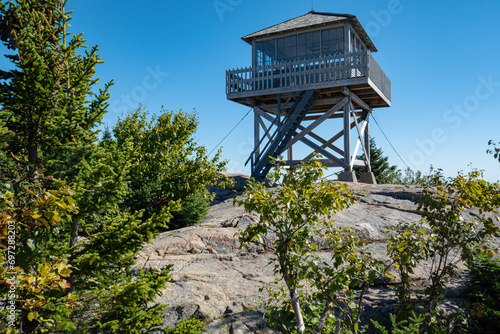 Fire tower in NH White Mountain National Forest built on a ledge reenforced with steel cables. Tower has walk around deck and windows to see in all directions.
