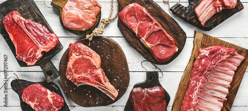 Set of various raw meat steaks. Fresh meat of beef, pork, veal, chicken, steak t-bone, rib eye, tomahawk, ribs, tenderloin on cutting board over white background. Meat food, butcher shop, top view photo