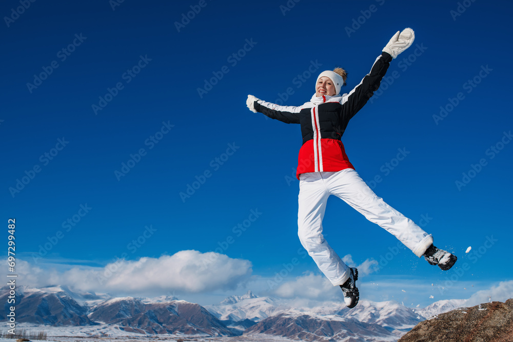 Happy woman tourist jumping on mountains background in winter Happy woman tourist jumping on mountains background in winter