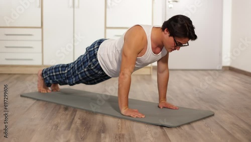 a young guy with glasses was doing push-ups at home on a mat, not in sportswear