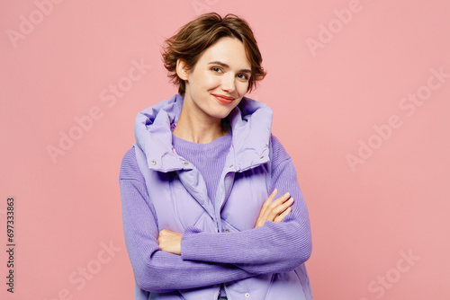 Young smiling happy cool woman she wear purple vest sweatshirt casual clothes hold hands crossed folded look camera isolated on plain pastel light pink background studio portrait. Lifestyle concept.