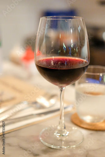 A glass of red wine on the table, with blur background in the restaurant