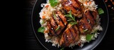 Asian style honey soy grilled chicken thighs with rice on a dark stone table, seen from above.