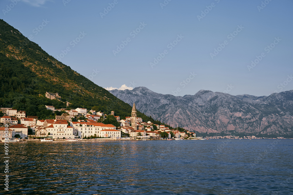 Bell tower of the church of St. Nicholas in Perast among old houses with red roofs. Montenegro